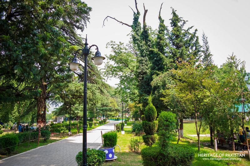 A peaceful walkway lined with shaped greenery welcomes visitors to Lady Garden